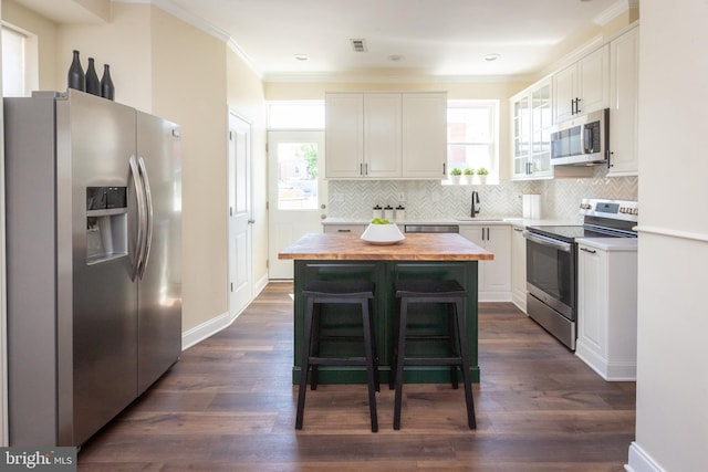 kitchen featuring decorative backsplash, a sink, butcher block counters, stainless steel appliances, and white cabinetry