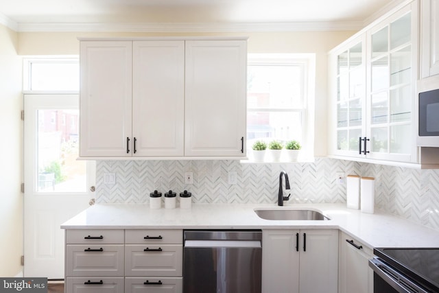 kitchen with stainless steel dishwasher, white cabinets, decorative backsplash, and a sink