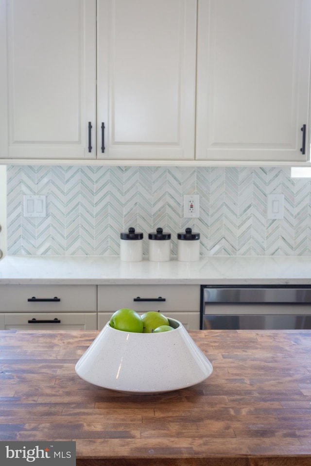 kitchen with butcher block countertops, decorative backsplash, white cabinetry, and dishwasher
