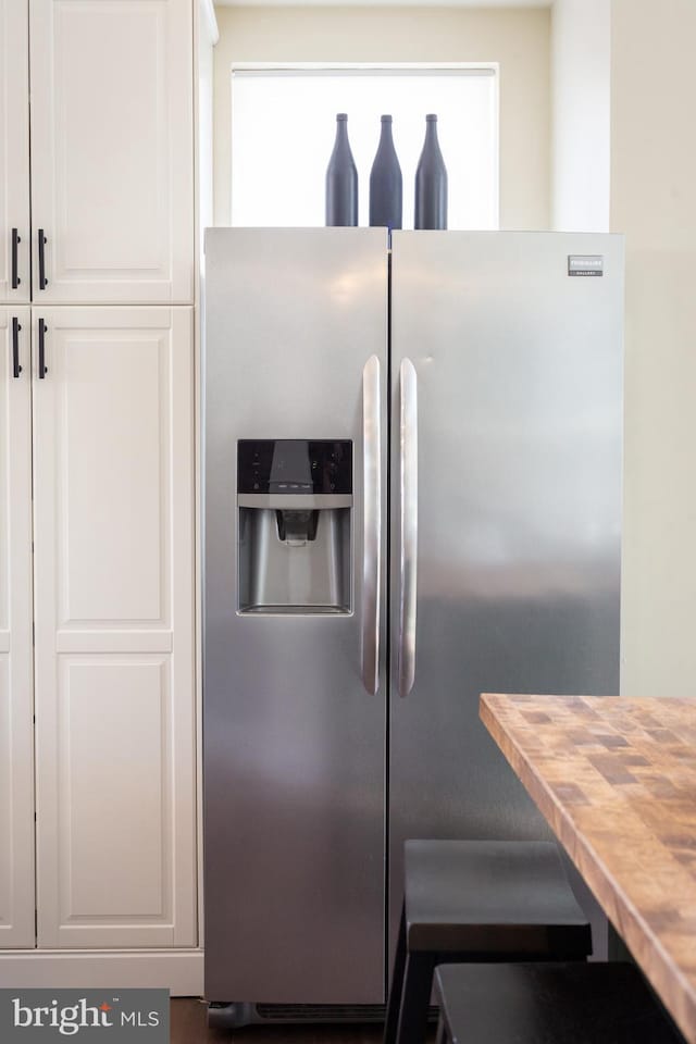kitchen with white cabinets, stainless steel refrigerator with ice dispenser, and butcher block countertops