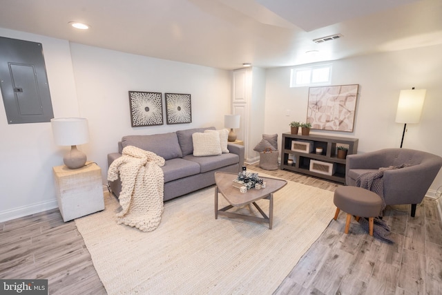 living area featuring light wood-style floors, baseboards, electric panel, and visible vents