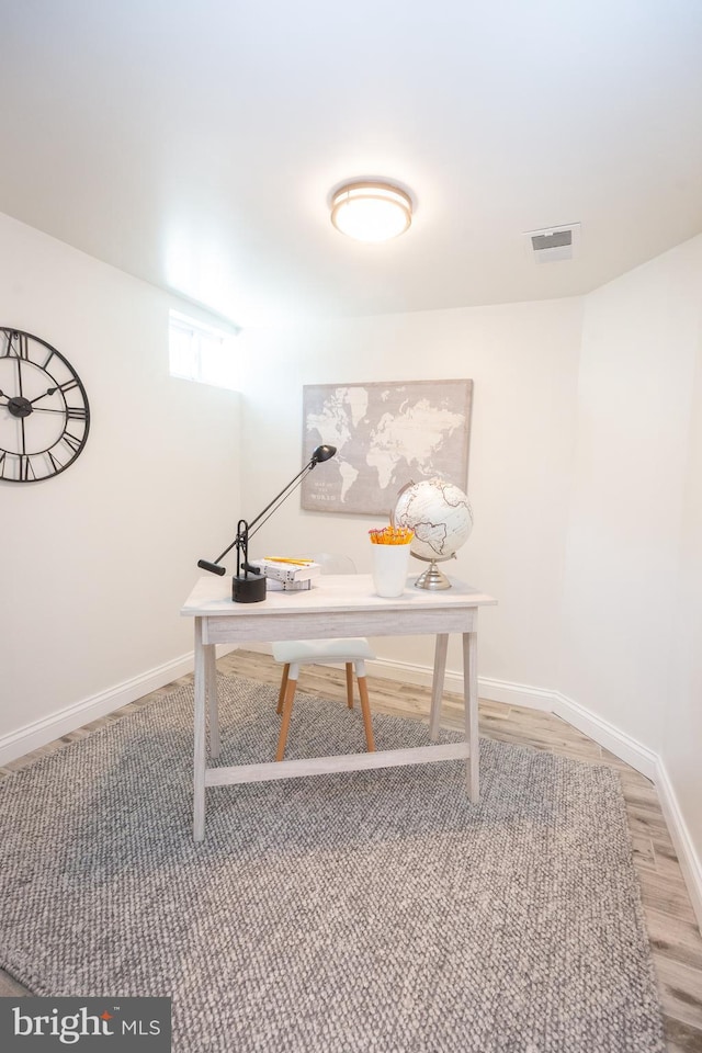 office space with baseboards, light wood-type flooring, and visible vents