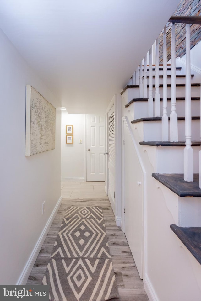 hallway featuring baseboards, stairs, and wood finished floors