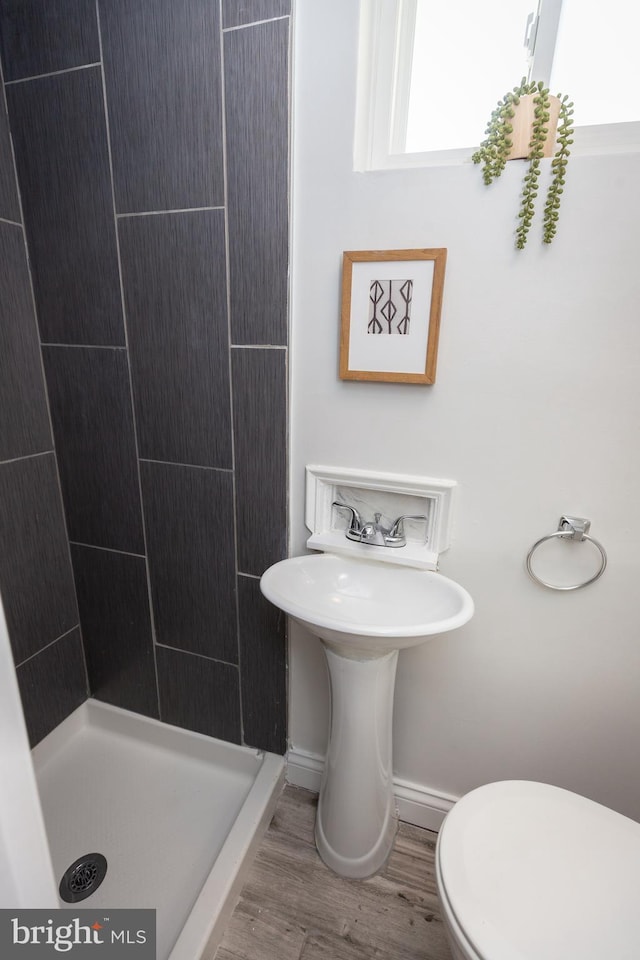 bathroom featuring baseboards, a stall shower, toilet, and wood finished floors
