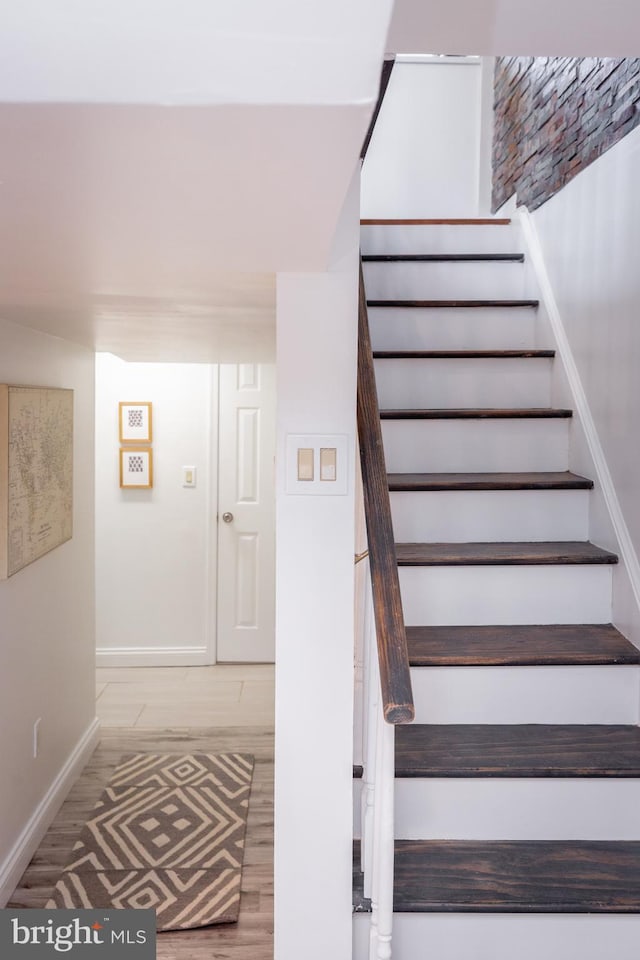 staircase with baseboards and wood finished floors