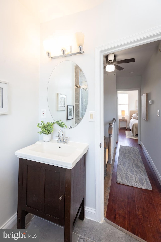 bathroom with a ceiling fan, baseboards, wood finished floors, and vanity