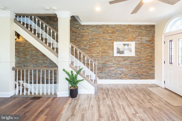 entrance foyer with ceiling fan, ornamental molding, stairs, and wood finished floors