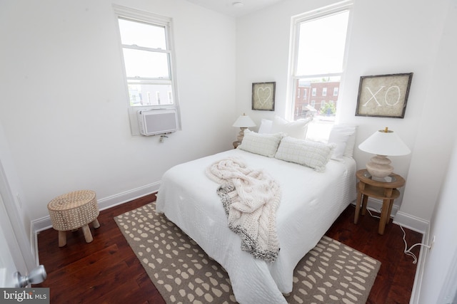 bedroom featuring baseboards, wood finished floors, multiple windows, and cooling unit