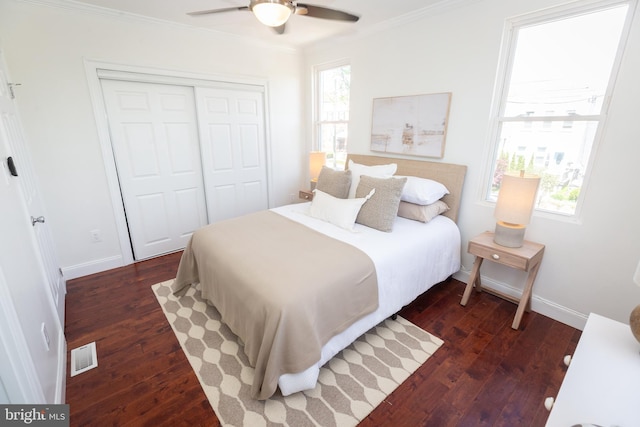bedroom featuring crown molding, visible vents, a closet, baseboards, and dark wood-type flooring
