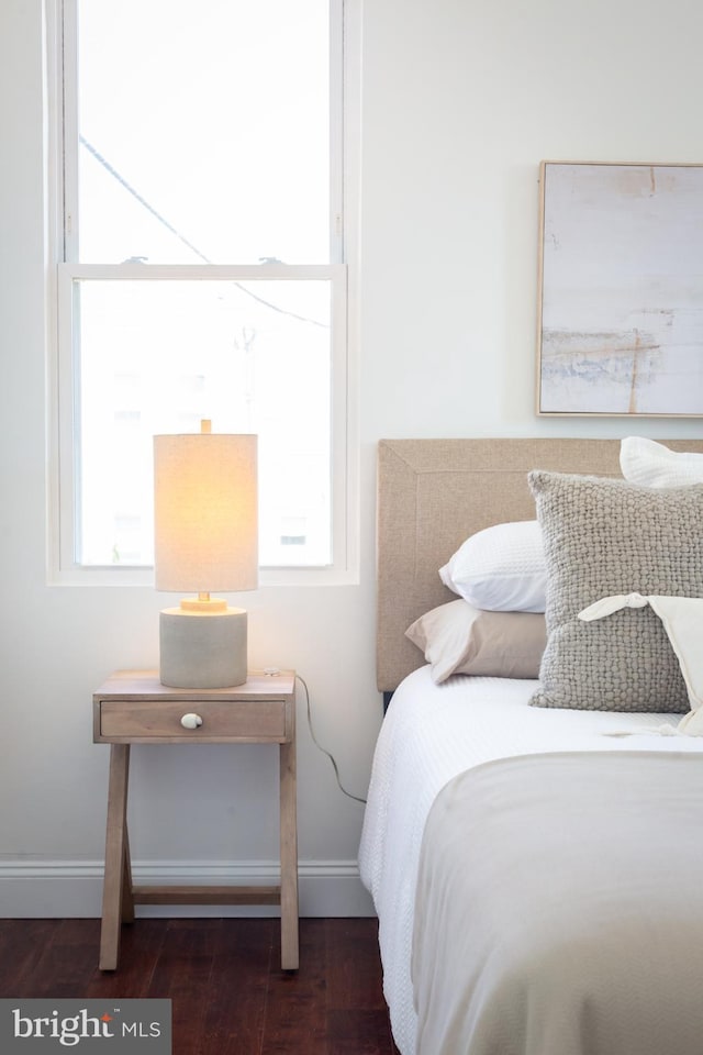 bedroom with baseboards, wood finished floors, and multiple windows