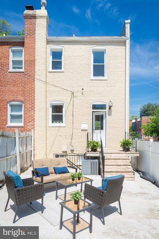 back of property with a patio, outdoor lounge area, fence, and a chimney