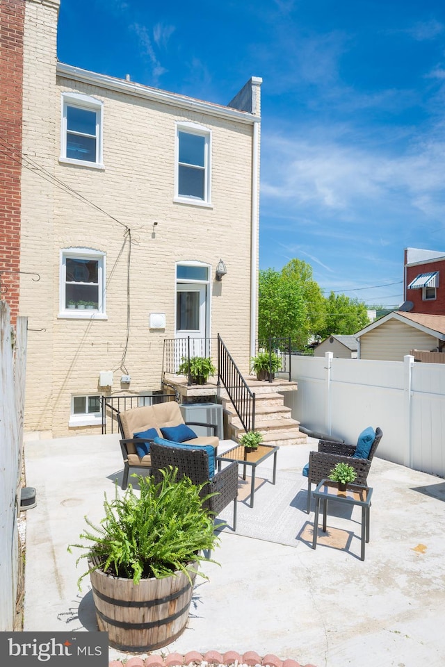 rear view of house with brick siding, fence, an outdoor hangout area, and a patio area