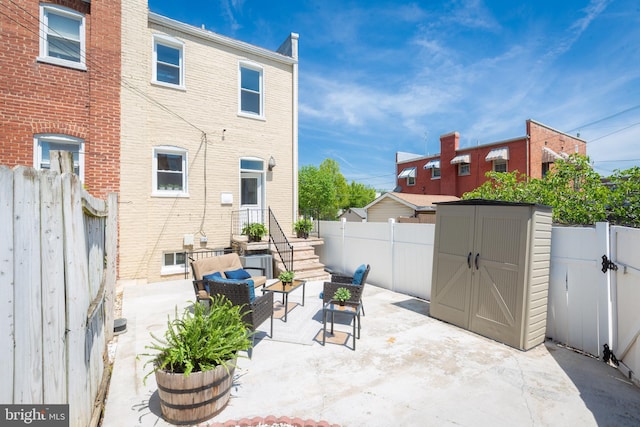 view of patio / terrace with a fenced backyard, a storage unit, an outdoor structure, and outdoor lounge area