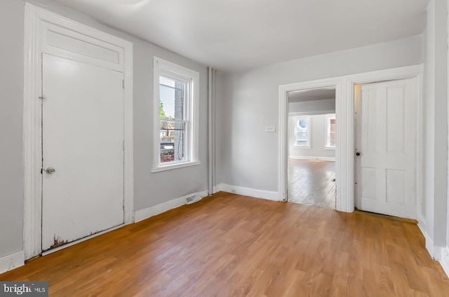 foyer entrance featuring a healthy amount of sunlight, baseboards, light wood finished floors, and visible vents
