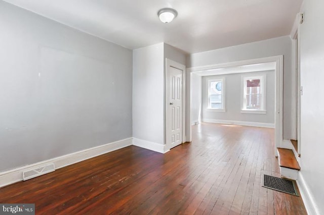 unfurnished room with wood-type flooring, baseboards, and visible vents