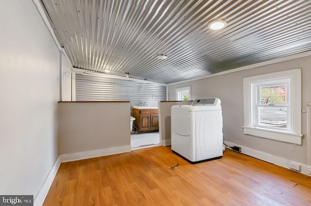 laundry area featuring washer / clothes dryer, laundry area, baseboards, and light wood-style flooring