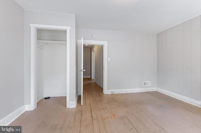 unfurnished bedroom with a closet, baseboards, visible vents, and light wood-type flooring