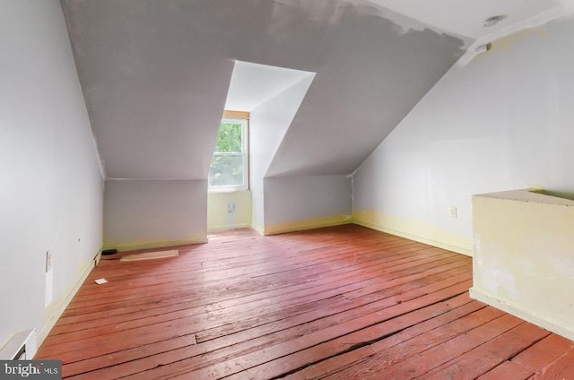 additional living space with wood-type flooring, baseboards, and lofted ceiling