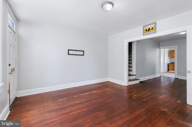 spare room with wood-type flooring, baseboards, and stairway