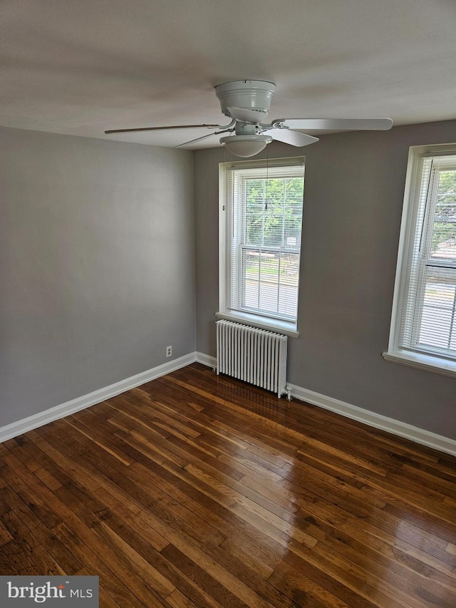 empty room featuring baseboards, a ceiling fan, radiator heating unit, and hardwood / wood-style flooring