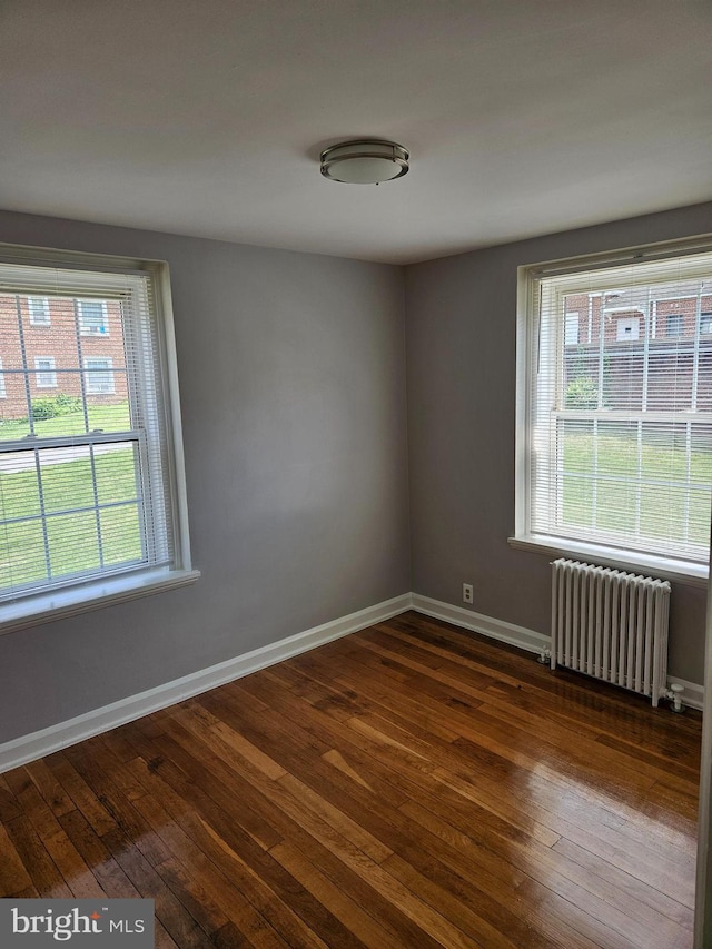 unfurnished room featuring baseboards, radiator, and dark wood-style floors