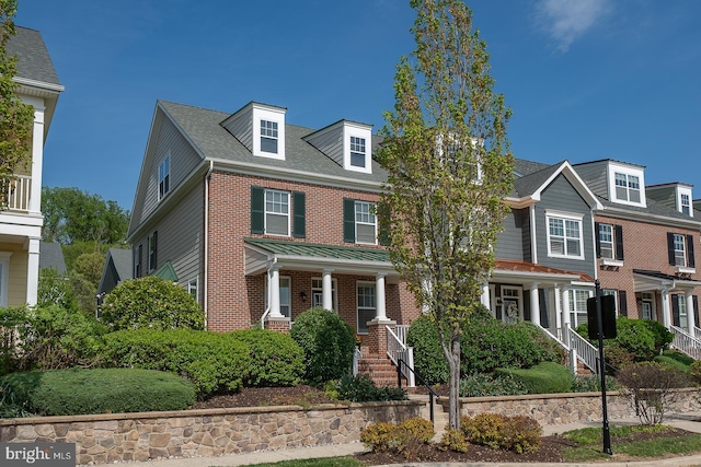 view of front facade with brick siding and covered porch