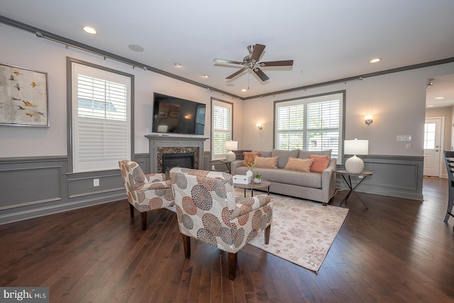 living area featuring crown molding, ceiling fan, a decorative wall, and dark wood-style flooring
