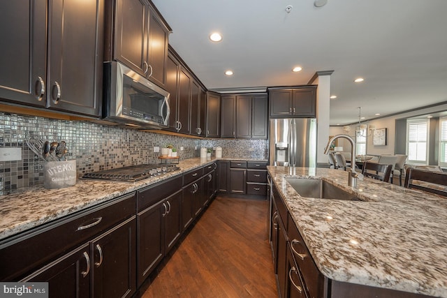 kitchen featuring dark brown cabinets, light stone countertops, dark wood-type flooring, a sink, and appliances with stainless steel finishes