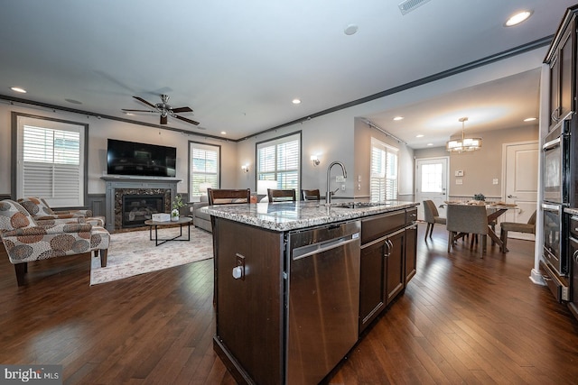 kitchen featuring dark wood-style flooring, a fireplace, dark brown cabinets, a sink, and stainless steel appliances