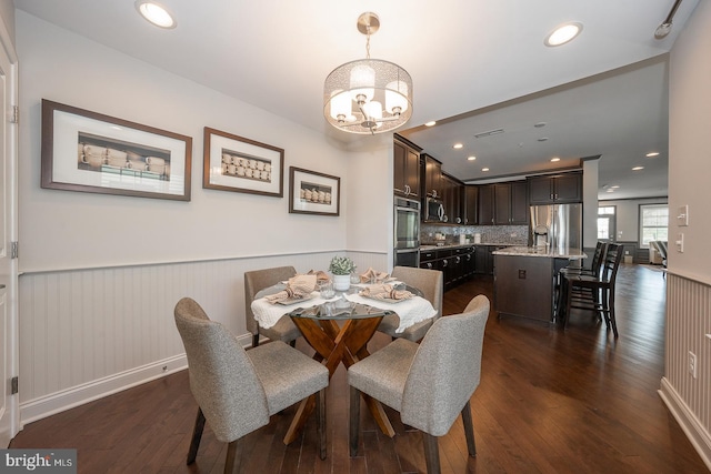 dining area featuring recessed lighting, a wainscoted wall, dark wood finished floors, and a notable chandelier