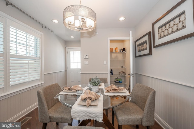 dining room with wood finished floors, recessed lighting, a wainscoted wall, and an inviting chandelier