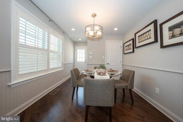 dining room with dark wood-style flooring, baseboards, an inviting chandelier, and a wainscoted wall