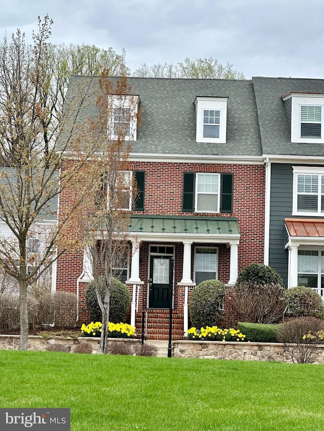 view of front facade featuring brick siding, a front lawn, and roof with shingles