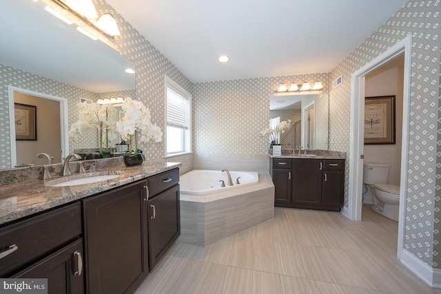 bathroom featuring a garden tub, a sink, visible vents, and wallpapered walls
