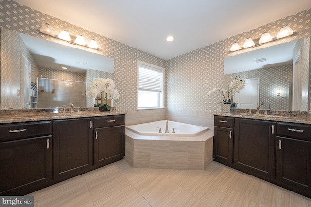 bathroom featuring a tile shower, two vanities, a sink, and a garden tub