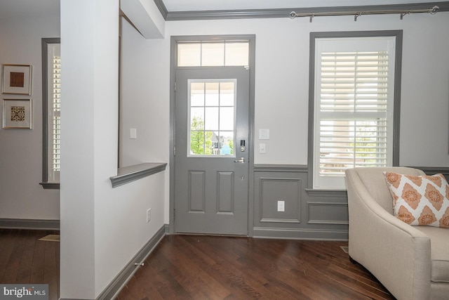 entryway with dark wood-type flooring, ornamental molding, and a wainscoted wall