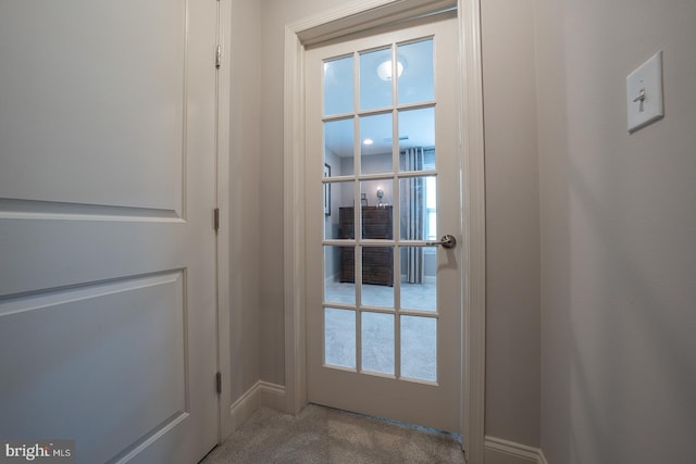 doorway featuring baseboards and carpet floors
