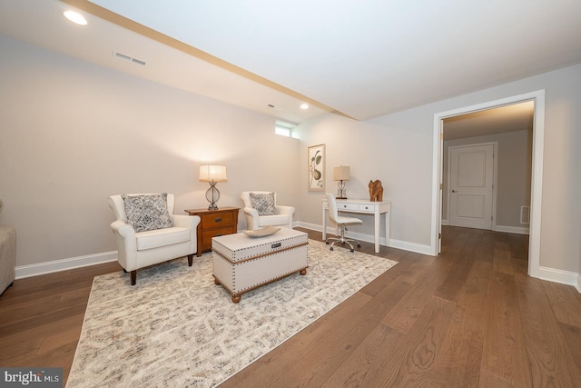 living area with baseboards, visible vents, and wood finished floors