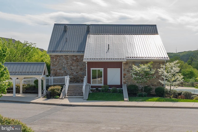view of front of property featuring stairway, a standing seam roof, metal roof, and stone siding