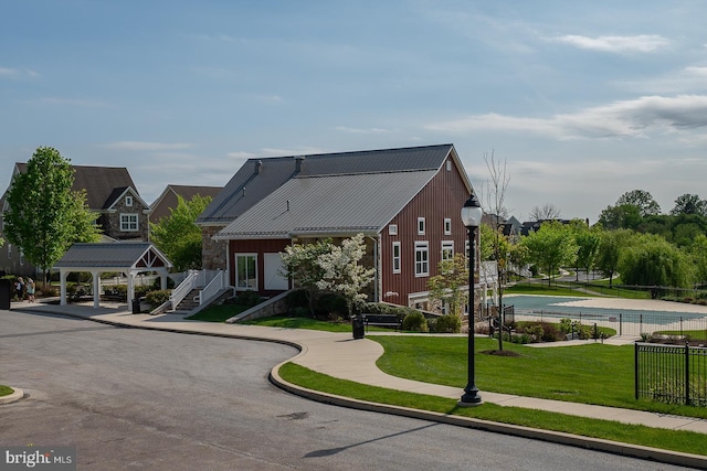 view of front of house featuring a front lawn, fence, stone siding, and metal roof