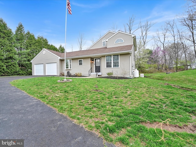 view of front of house with an attached garage, a front lawn, and aphalt driveway