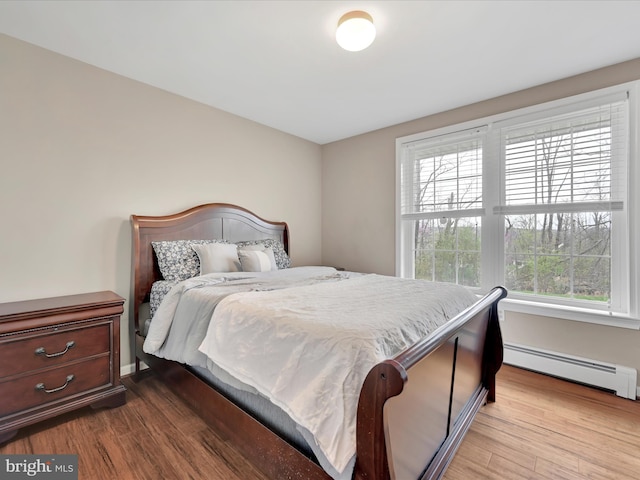 bedroom featuring wood finished floors and a baseboard heating unit
