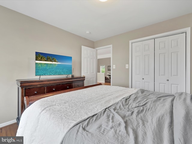 bedroom with baseboards, wood finished floors, and a closet