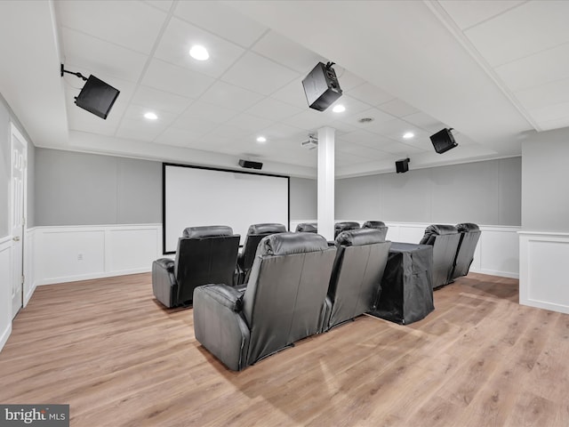 home theater room featuring a wainscoted wall, a decorative wall, light wood-type flooring, and a paneled ceiling