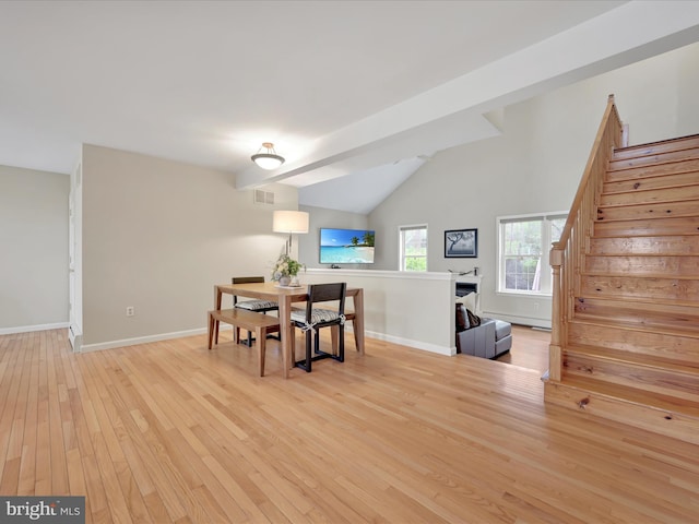 dining area featuring baseboards, lofted ceiling, light wood-type flooring, visible vents, and stairway