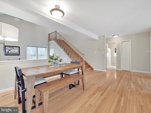 dining space with light wood-style floors, baseboards, and stairway