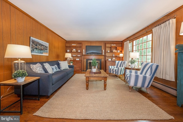 living area with a fireplace, dark wood-style flooring, wooden walls, and baseboard heating