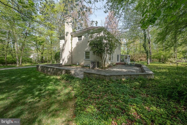 back of property featuring a yard, a patio area, a chimney, and central air condition unit
