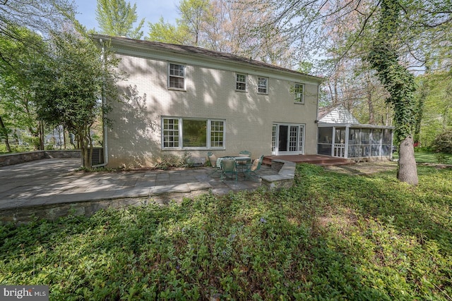 rear view of property featuring a yard, a sunroom, a patio, and brick siding