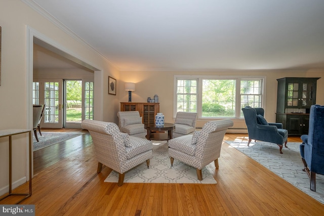 living room featuring a baseboard heating unit, ornamental molding, and light wood-style flooring